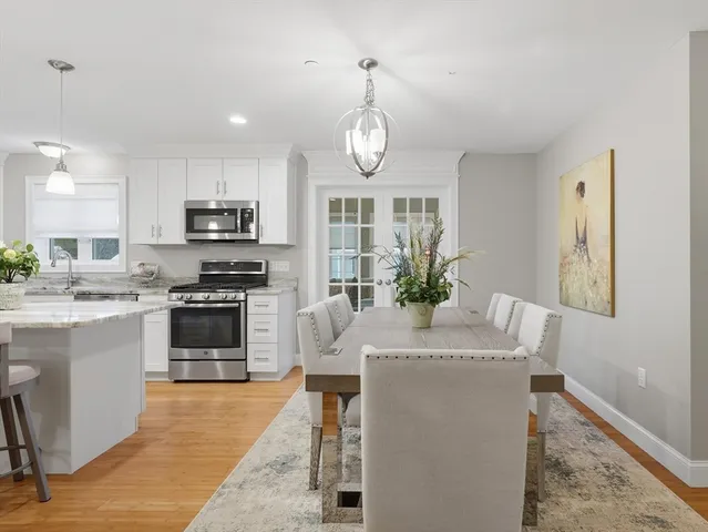 a view of a dining room and livingroom with furniture wooden floor a chandelier