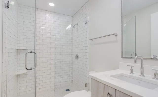 a bathroom with a shower sink vanity and mirror