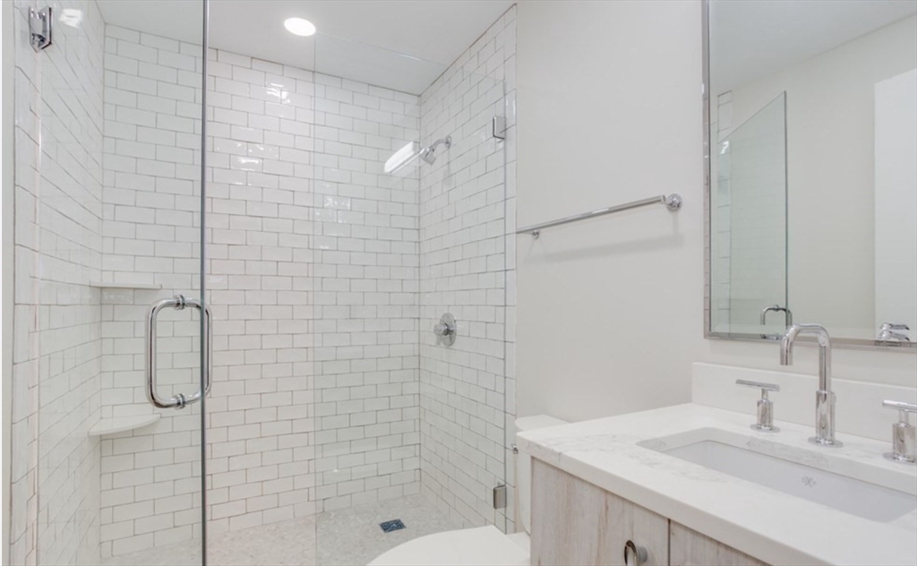 63 Melcher Street, Unit 404 Boston, MA 02210 - Photo 7 of 12 a bathroom with a shower sink vanity and mirror