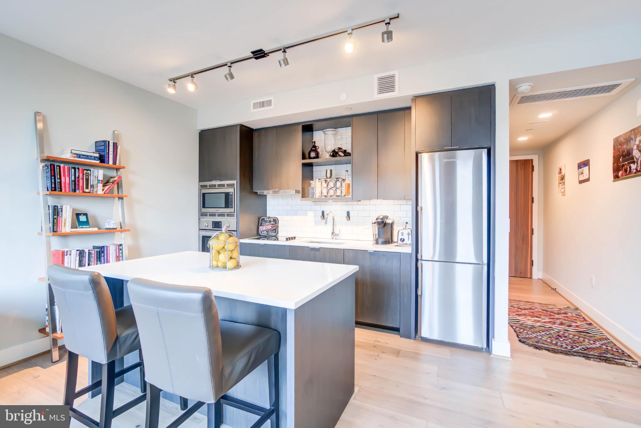 1300 4th Street Southeast, Unit 414 Washington, DC 20003 - Photo 1 of 31 a kitchen with stainless steel appliances granite countertop a dining table chairs refrigerator and sink