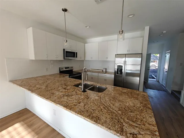 a kitchen with granite countertop a sink a counter top space appliances and cabinets