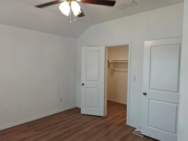 an empty room with wooden floor closet and windows