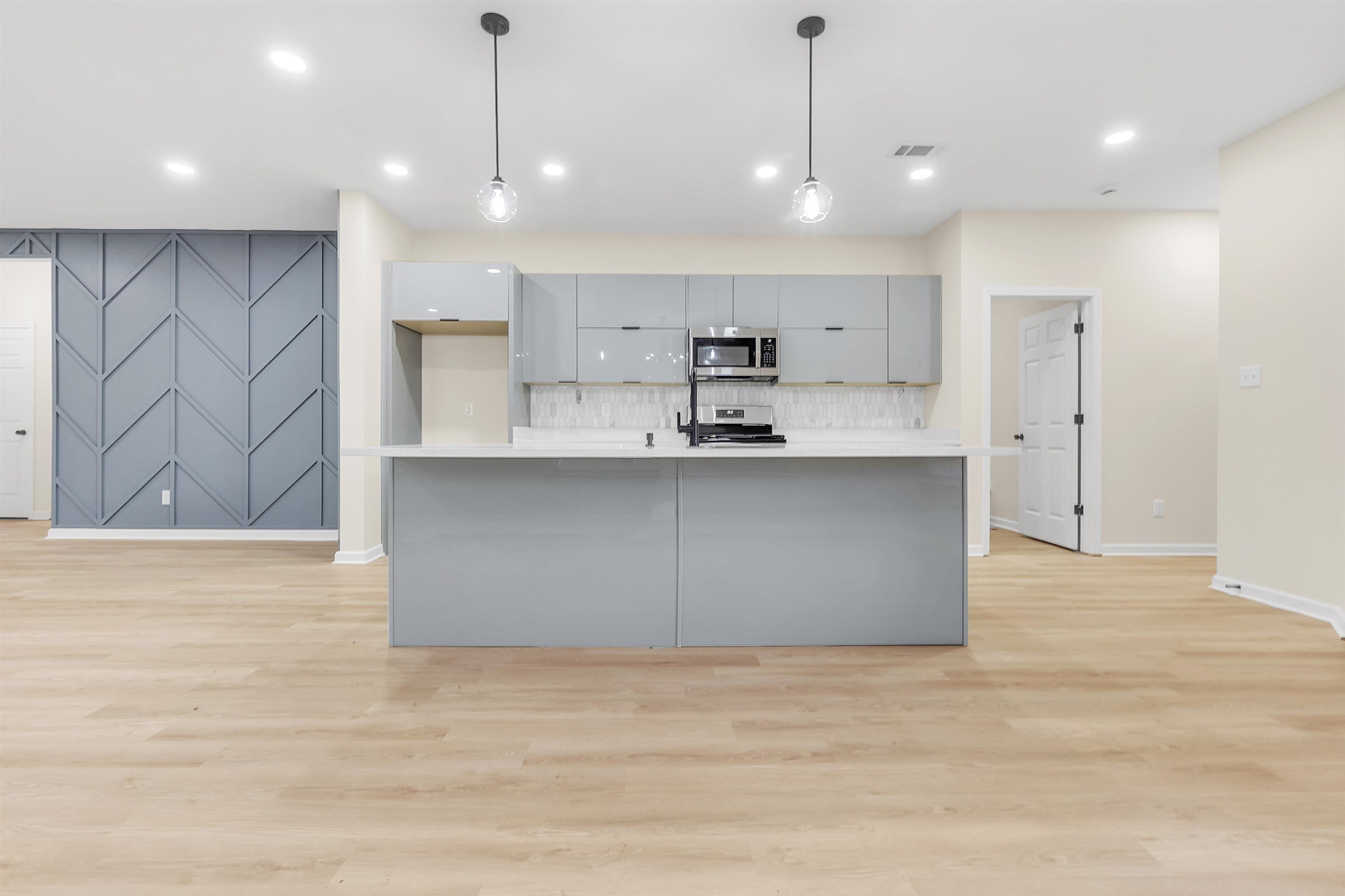 4397 Crescent Park Drive Memphis, TN 38141 - Photo 13 of 40 Kitchen with light wood-type flooring, gray cabinetry, an accent wall, modern cabinets, and appliances with stainless steel finishes