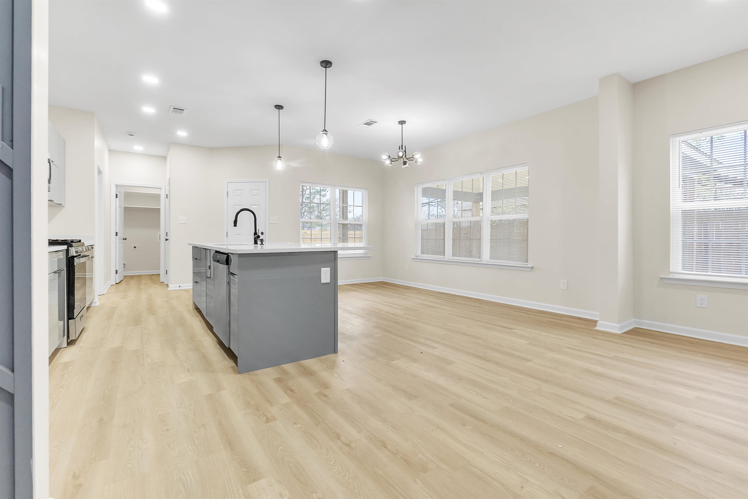 4397 Crescent Park Drive Memphis, TN 38141 - Photo 14 of 40 Kitchen featuring a healthy amount of sunlight, light wood-type flooring, stainless steel range with gas cooktop, a sink, and a notable chandelier
