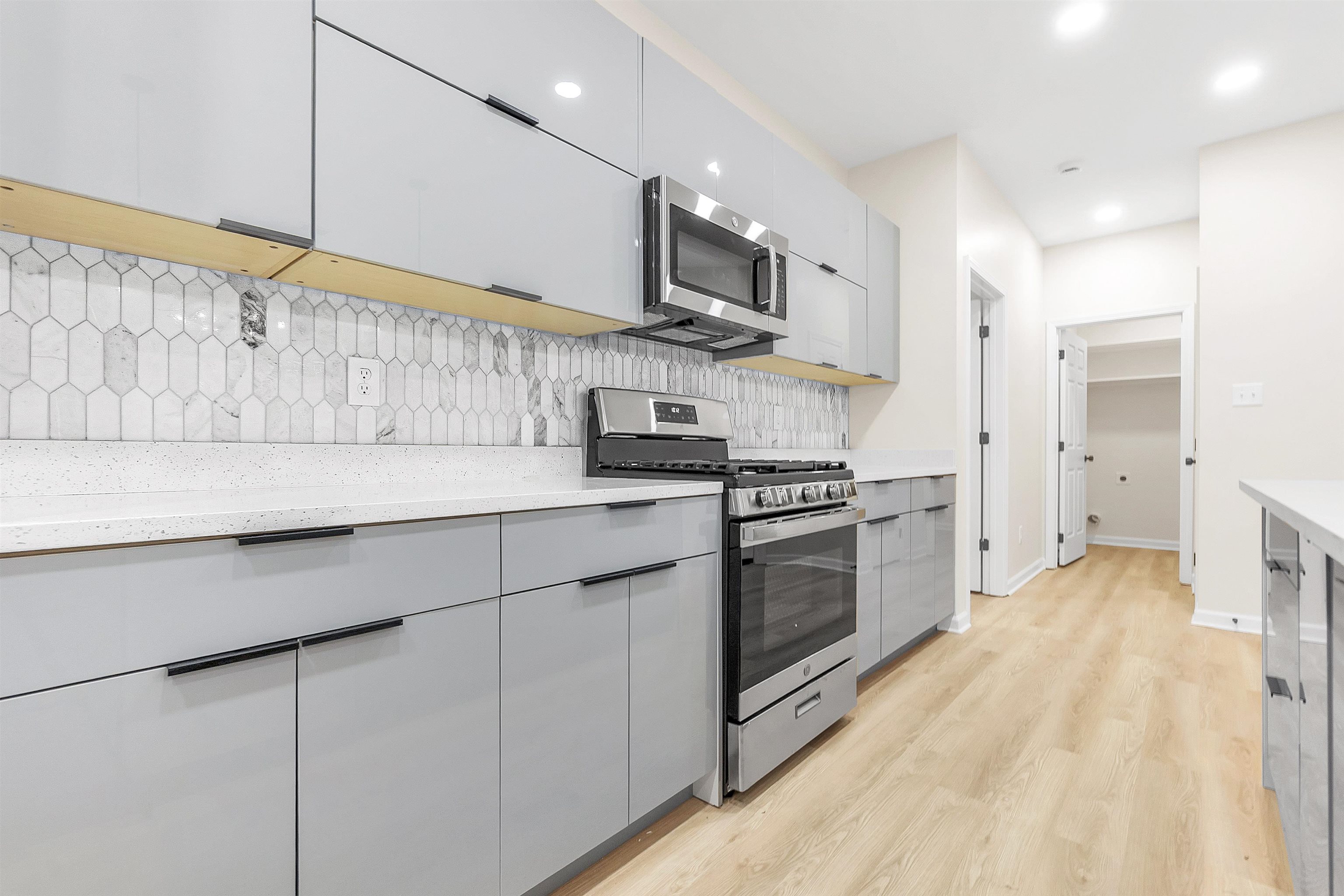 4397 Crescent Park Drive Memphis, TN 38141 - Photo 8 of 40 Kitchen with light wood-style flooring, modern cabinets, appliances with stainless steel finishes, gray cabinetry, and backsplash