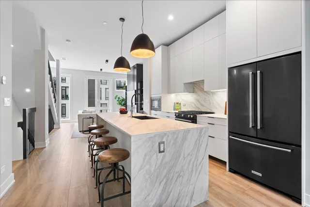 a kitchen with stainless steel appliances a dining table chairs stove and refrigerator