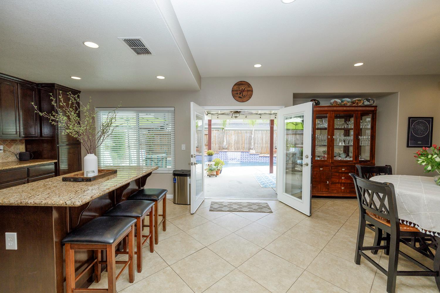 3416 Will Scarlet Way Modesto, CA 95355 - Photo 19 of 56 a dining hall with stainless steel appliances granite countertop a stove a sink a dining table and chairs with wooden floor