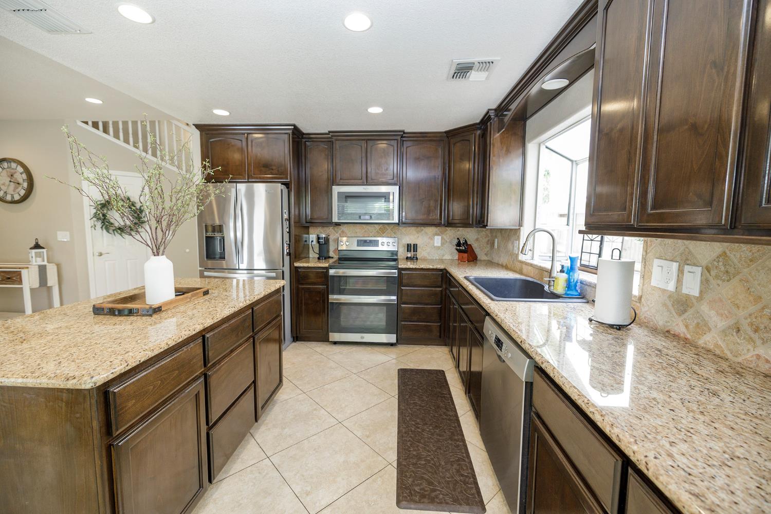 3416 Will Scarlet Way Modesto, CA 95355 - Photo 23 of 56 a kitchen with stainless steel appliances granite countertop a sink stove and refrigerator