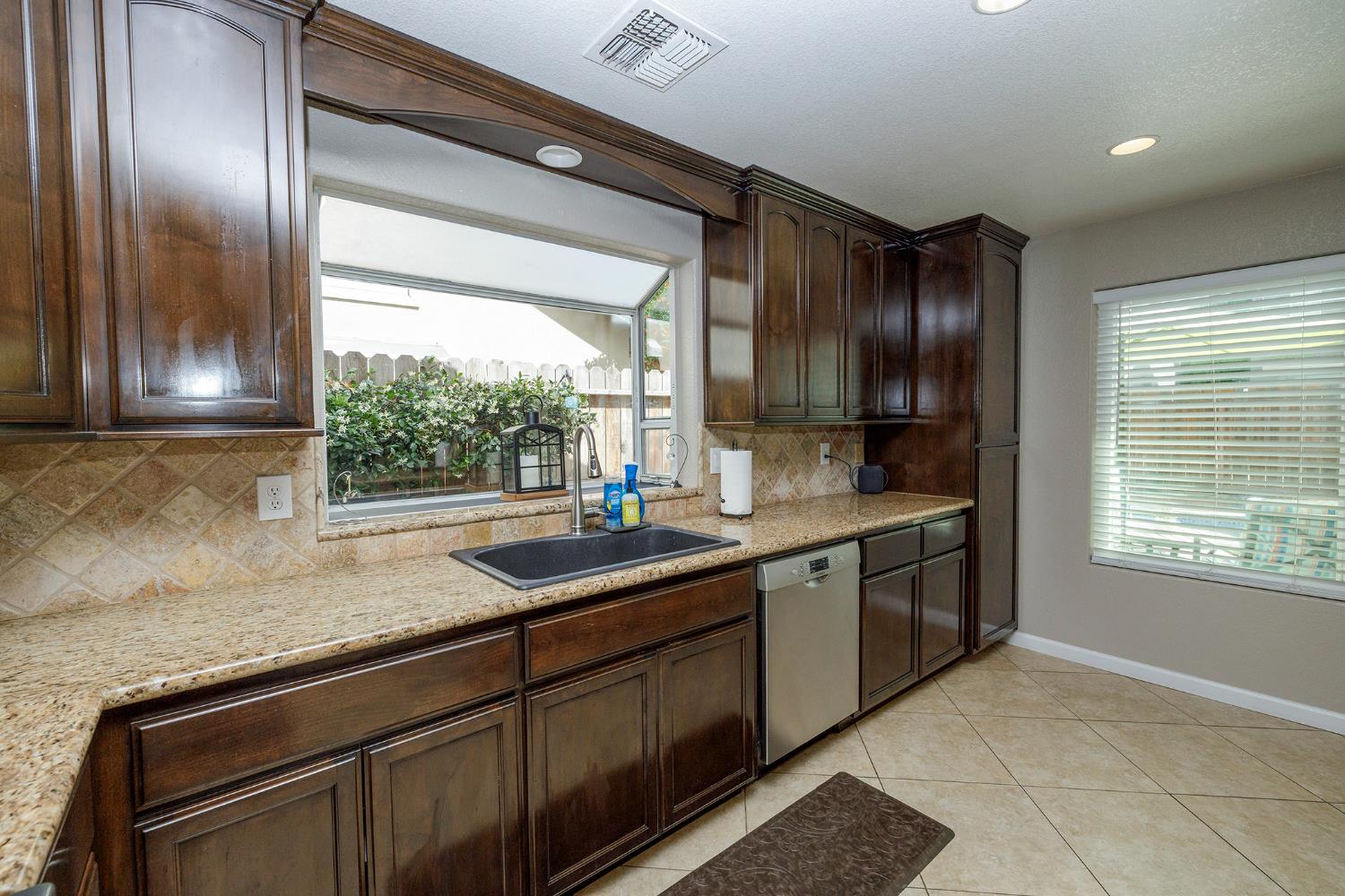 3416 Will Scarlet Way Modesto, CA 95355 - Photo 24 of 56 a kitchen with granite countertop stainless steel appliances window a sink and cabinets