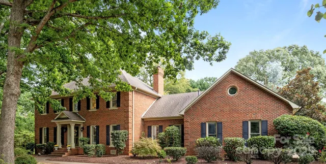 a view of a yard in front of a brick house with large windows