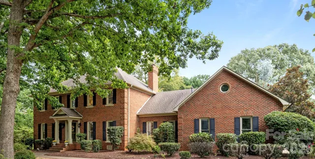 a view of a yard in front of a brick house with large windows