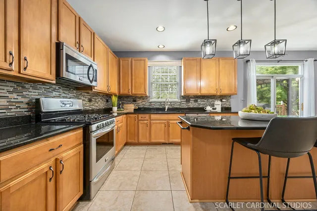 a kitchen with stainless steel appliances granite countertop a refrigerator a sink dishwasher a stove and white cabinets next to a window