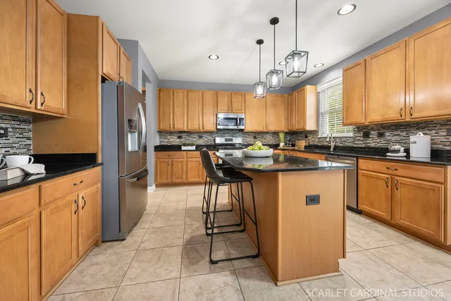 a kitchen with stainless steel appliances granite countertop wooden cabinets a sink a stove and a refrigerator