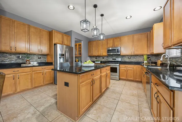 a kitchen with stainless steel appliances granite countertop a stove top oven a refrigerator a sink and dishwasher with white cabinets