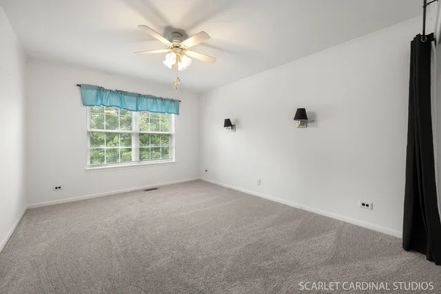 an empty room with windows and fan