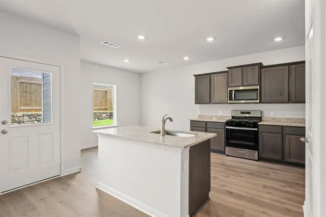 a kitchen with stainless steel appliances granite countertop a sink stove and refrigerator