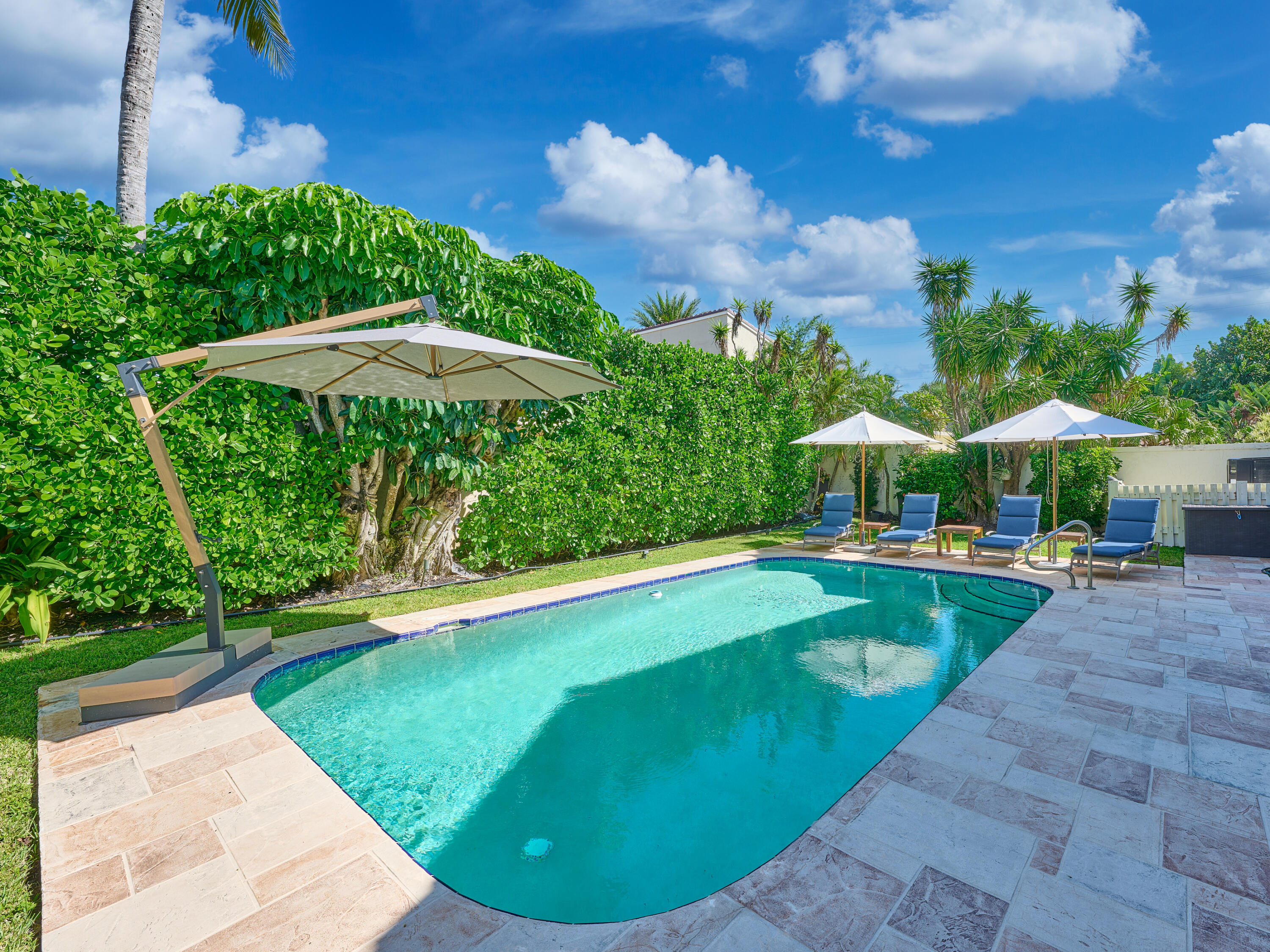 Undisclosed Address Jupiter, FL 33477 - Photo 19 of 20 a view of a swimming pool with lawn chairs under an umbrella