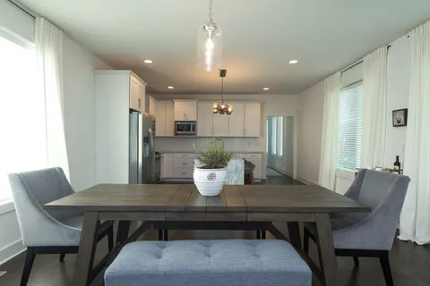 a kitchen with a dining table chairs and refrigerator