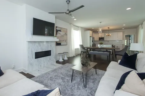 a living room with stainless steel appliances furniture a fireplace a flat screen tv and view kitchen