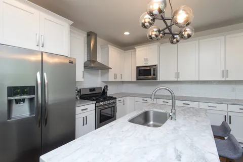 a kitchen with stainless steel appliances granite countertop a refrigerator a sink dishwasher a stove oven and white cabinets