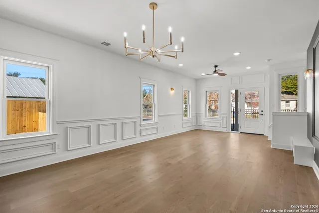 a view of an empty room with a window and wooden floor