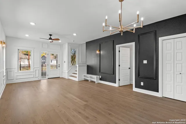 a view of an empty room with kitchen and window