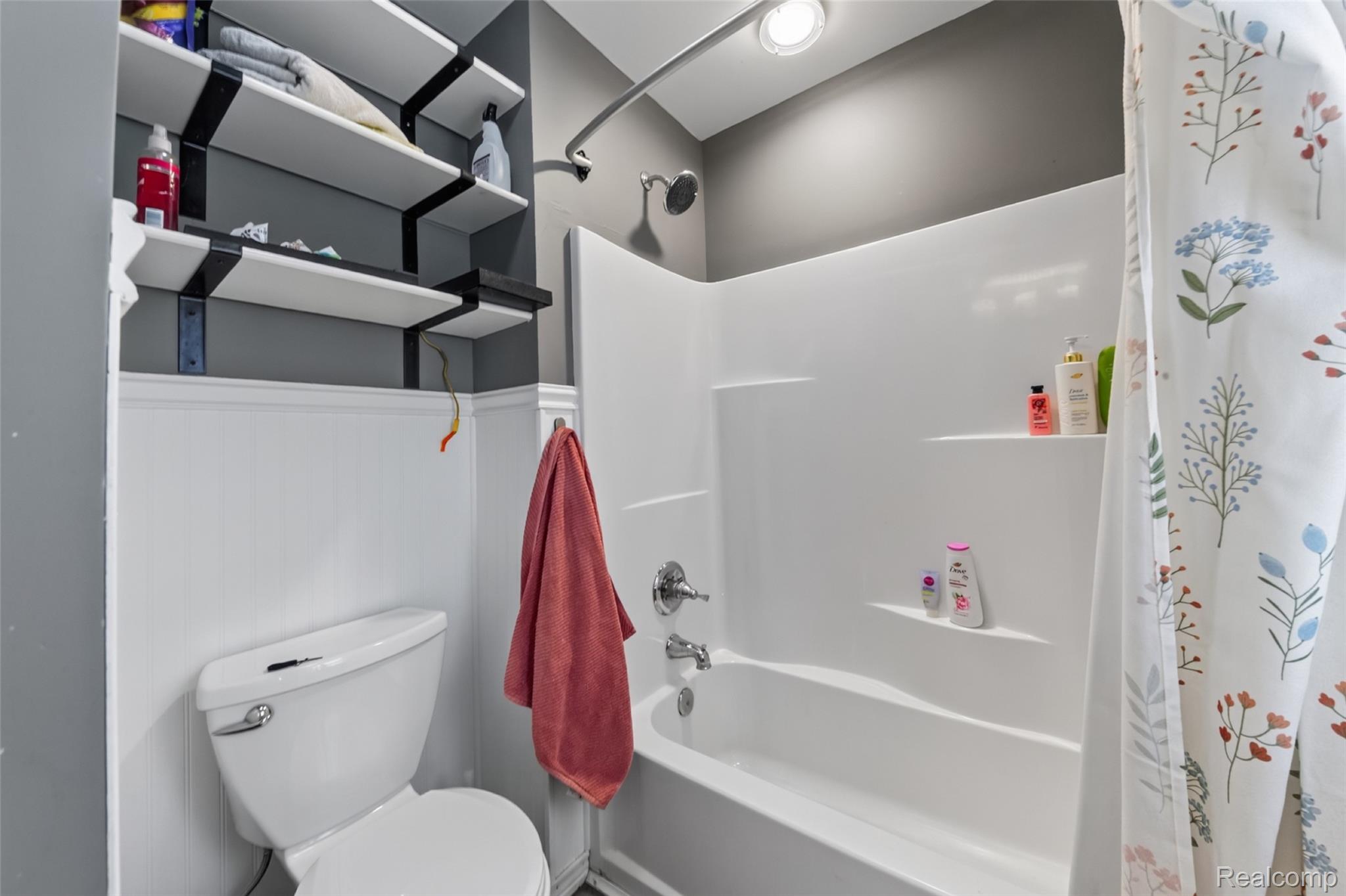 7447 Ore Lake Road Brighton, MI 48116 - Photo 30 of 45 Bathroom featuring a white bathtub/shower combination with chrome fixtures, a white toilet, and wainscoting