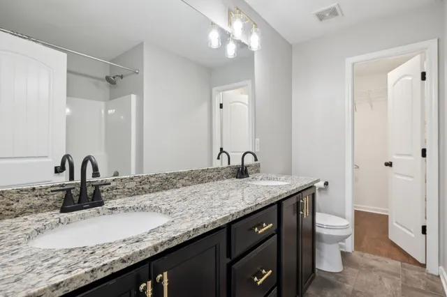 a bathroom with a granite countertop sink a toilet and a large mirror