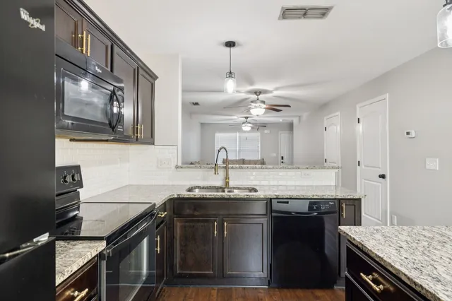 a kitchen with granite countertop a sink cabinets and stainless steel appliances