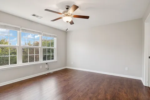 an empty room with wooden floor and windows