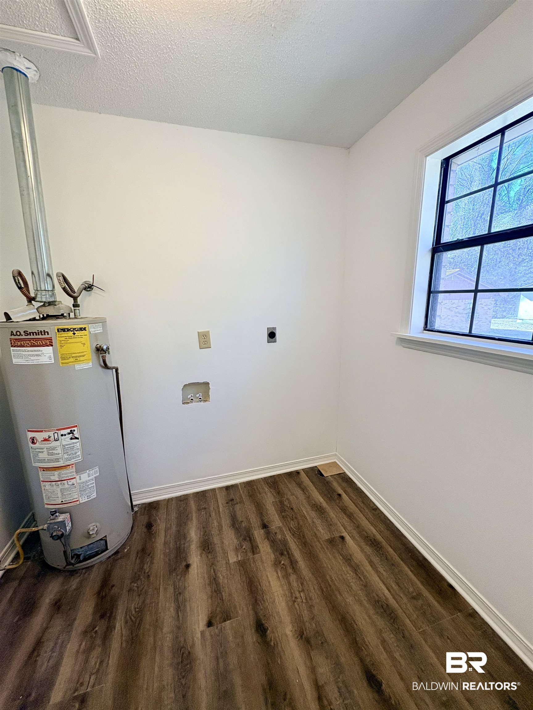 47 Fairview Street Evergreen, AL 36401 - Photo 10 of 15 Washroom with gas water heater, dark wood-type flooring, a textured ceiling, washer hookup, and hookup for an electric dryer