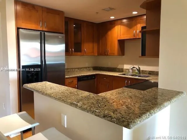 a kitchen with stainless steel appliances granite countertop a sink a stove and a refrigerator