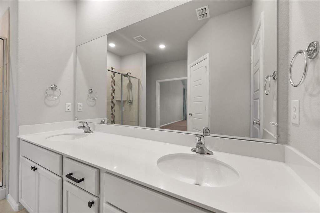 6910 Prairieside Trail Venus, TX 76084 - Photo 21 of 40 The bathroom features a double vanity with white cabinets, light-colored countertops, two undermount sinks and an oversized shower stall.