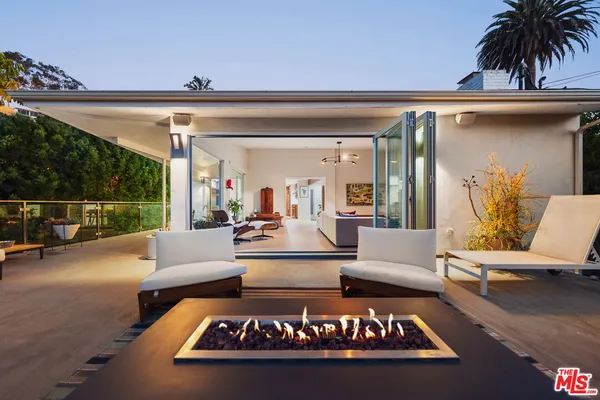 a view of a patio with couches table and chairs with potted plants and a barbeque