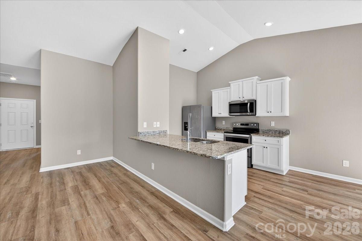 4322 One Mile Way Charlotte, NC 28215 - Photo 14 of 48 a kitchen with granite countertop white cabinets and wooden floor