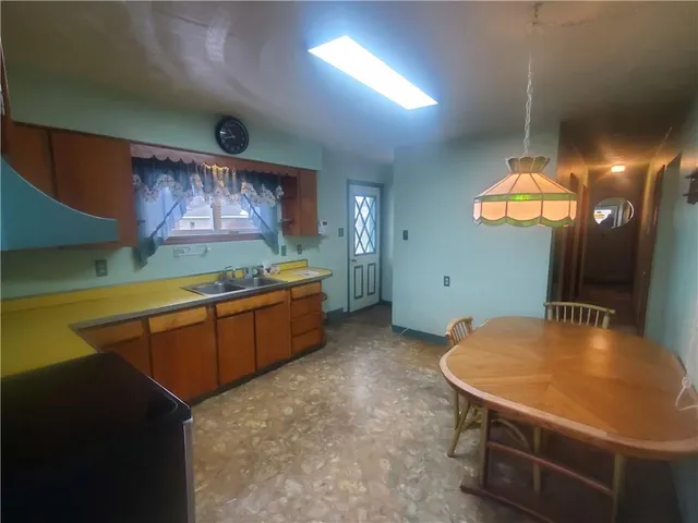 a kitchen with stainless steel appliances kitchen island a table chairs in it and a window