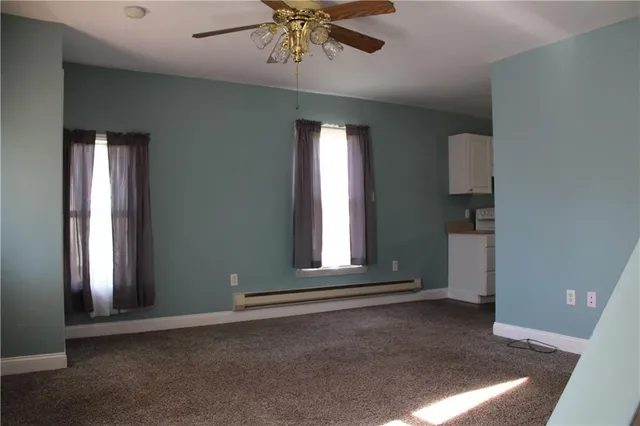 an empty room with windows and ceiling fan