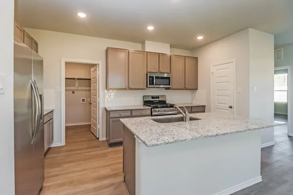 a kitchen with kitchen island granite countertop a sink stove and refrigerator