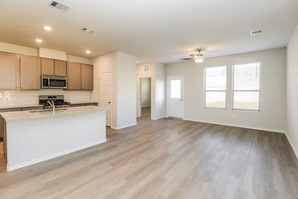 a view of kitchen with sink a microwave and cabinets