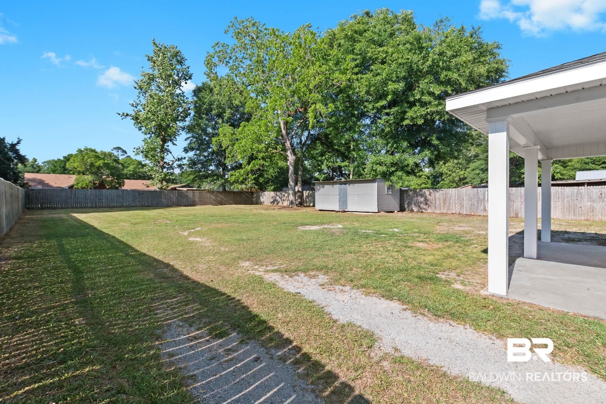 311 Cloverdale Road Atmore, AL 36502 - Photo 56 of 63 Expansive backyard with a covered patio, a detached storage shed, perimeter fencing, and mature trees