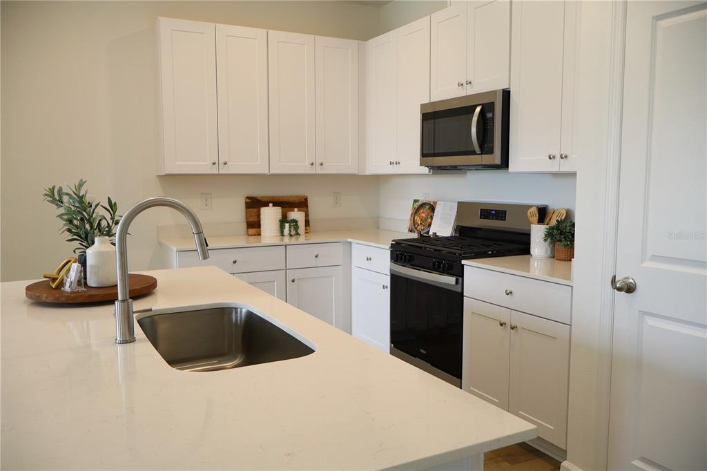 5719 Hiawassee Road Yalaha, FL 34797 - Photo 4 of 20 a kitchen with white cabinets and black appliances