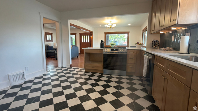 4883 South Center Street Murray, UT 84107 - Photo 8 of 32 Kitchen featuring checkerboard flooring, natural wood-finish cabinetry, stainless steel range, integrated dishwasher, and a stainless steel sink with a light-toned countertop
