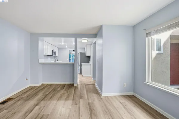 a view of an empty room with wooden floor and a window