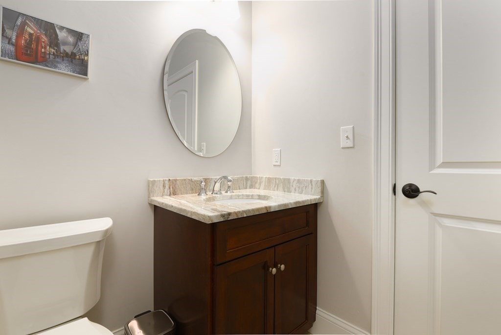 221 Valley Road Needham, MA 02492 - Photo 18 of 42 a bathroom with a granite countertop sink a toilet and a mirror