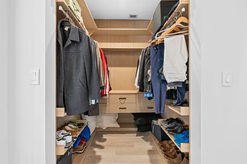 a view of walk in closet with clothes and shoes
