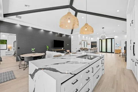 a large kitchen with a sink and living room view