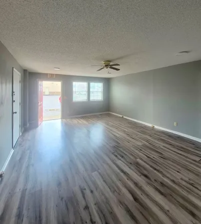 a view of an empty room with wooden floor and window