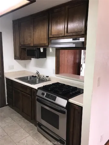 a kitchen with granite countertop stainless steel appliances a stove microwave and sink