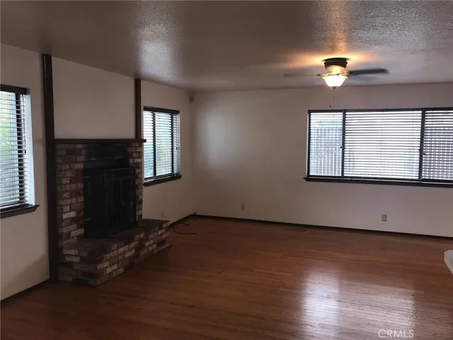 an empty room with wooden floor cabinet and windows