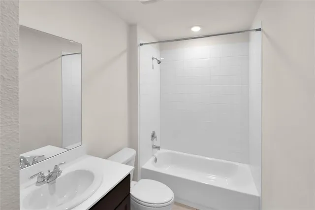 a bathroom with a bathtub shower sink vanity and toilet